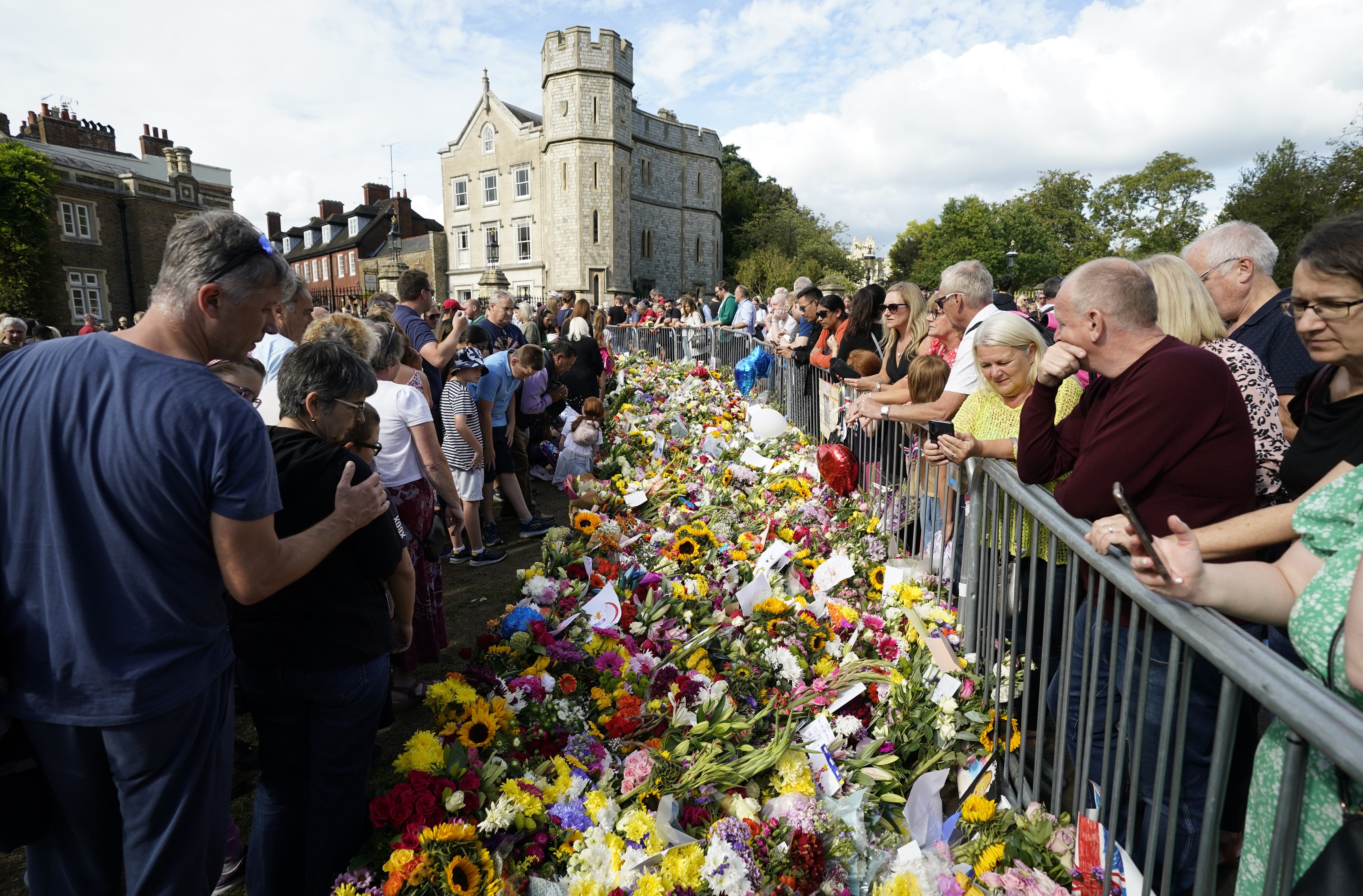Personas observan los tributos florales en honor a Isabel II en las afueras del Castillo de Windsor.