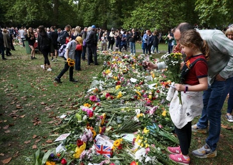 Imagen secundaria 1 - Arriba, Erik Karlsen con sus empleados, Roaika y Aleksander, en Pulbrook & Gould. Debajo, dos aspectos de Green Park, donde se están acumulando los ramos en memoria de Isabel II