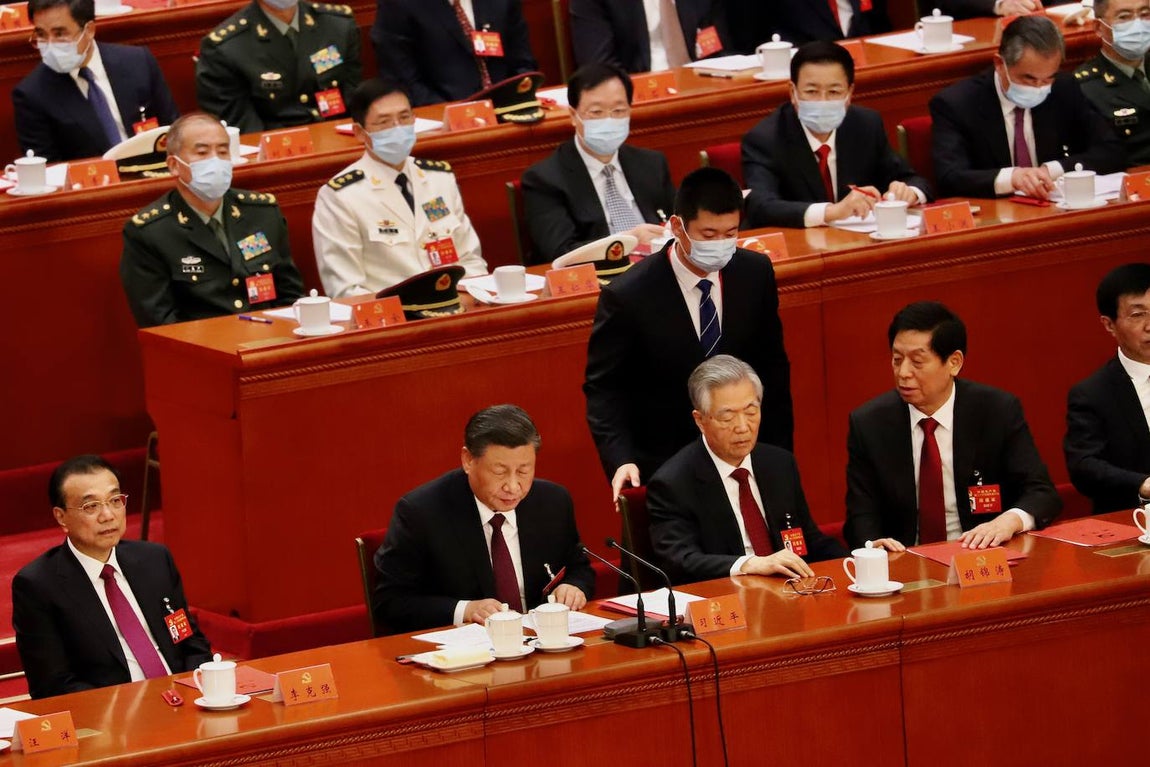 El bedel se acerca por detrás a Hu Jintao, cuyo rostro está muy serio. A su lado, Li Zhanshu y Wang Huning, ideólogo del régimen, también se muestran estupefactos.