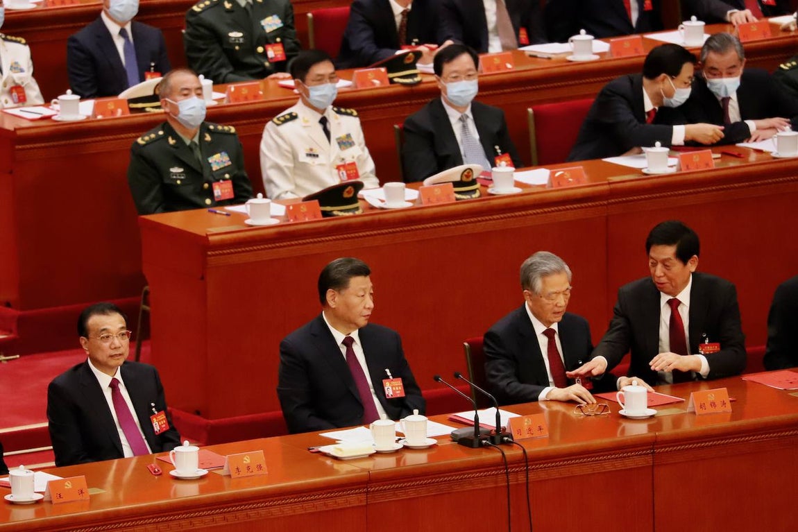 Hu Jintao, a la izquierda de Xi Jinping, toquetea una carpeta con documentos. A su lado está Li Zhanshu, número tres del régimen.