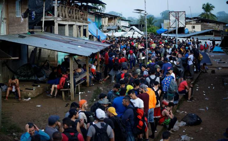 Imagen principal - Arriba, Migrantes hacen fila para ser enviados a una estación de recepción migratoria (ERM) de San Vicente en Metetí, el 14 de octubre de 2022, en el pueblo de Bajo Chiquito (Panamá); Debajo, un venezolano seca dólares empapados duranet el viaje; dos mujeres se abrazan tras cruzar el Darién