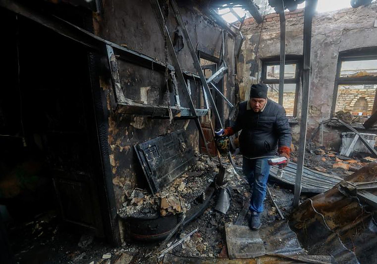 Pavel recoge algunos objtetos de su vecino muerto tras el bombardeo de su vivienda en Donetsk