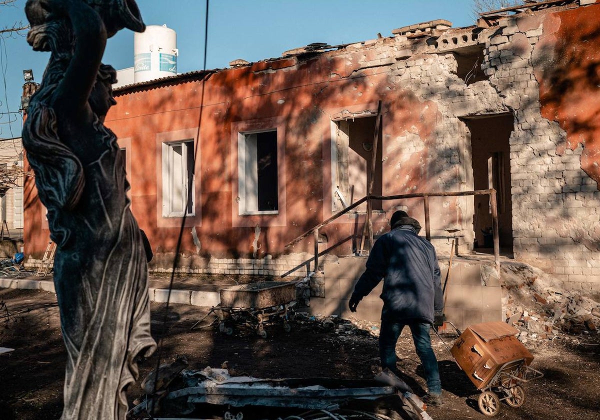 Un hombre lleva un carrito frente a una planta de maternidad bombardeada en Jersón