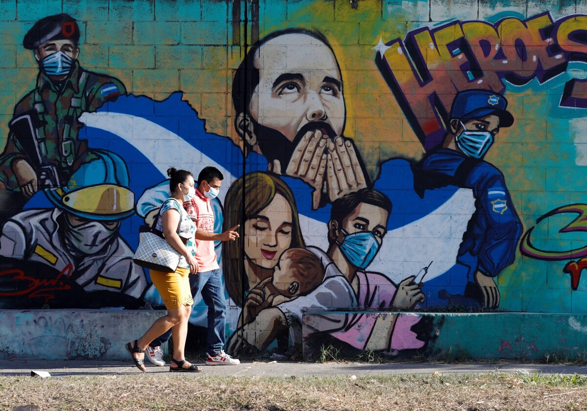 Un grupo de personas pasa junto a un graffiti que representa al presidente de El Salvador, Nayib Bukele, en Soyapango (El Salvador), una de las zonas que estaban bajo control de las pandillas