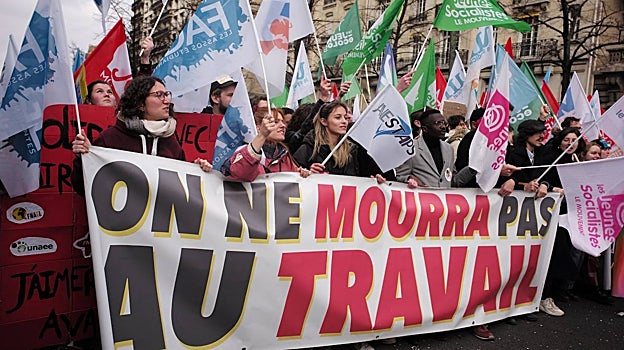 Un grupo de jóvenes sostiene una pancarta donde se lee: «No moriremos en el trabajo»