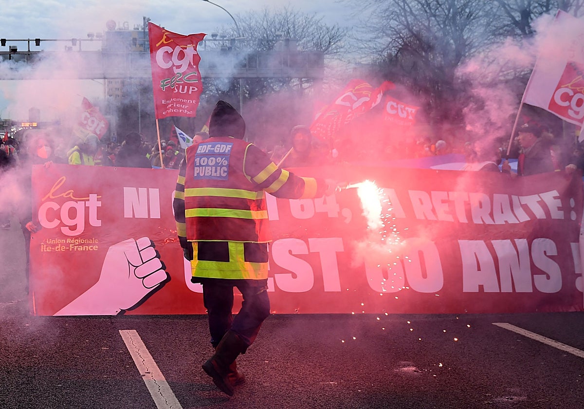 Sindicalistas de la CGT marchan con bengalas y pancartas por la circunvalación de París este viernes, mientras bloquean el tráfico para protestar, un día después de que el Gobierno francés impulsara la aprobación de la reforma de las pensiones con un decretazo