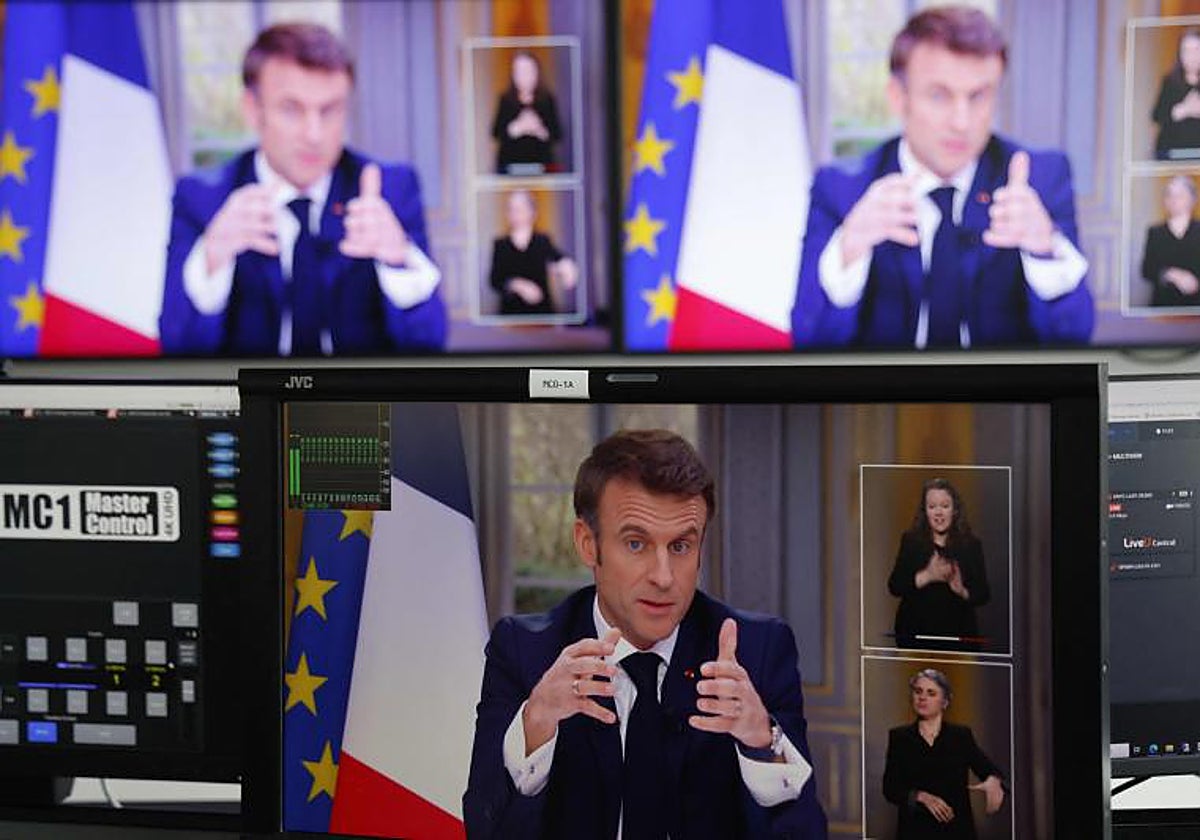 El presidente francés, Emmanuel Macron, se ve en las pantallas mientras habla durante una entrevista televisiva desde el Palacio del Elíseo