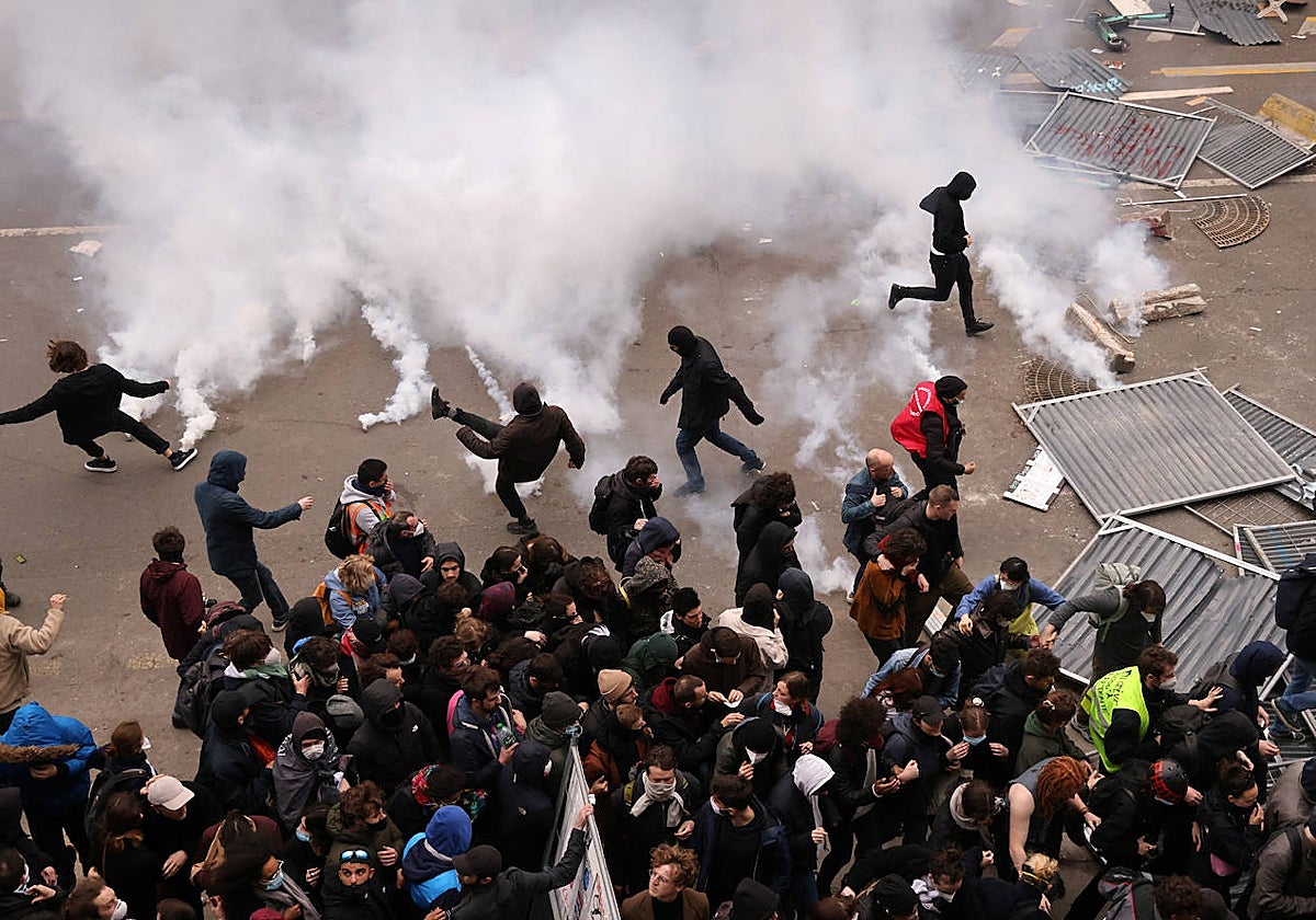 Un grupo de manifestantes devuelve botes de gas lacrimógeno durante las protestas en París