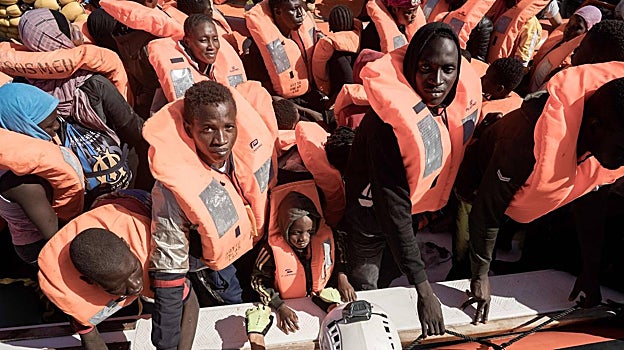 Migrantes se preparan para subir a un bote en aguas internacionales frente a Libia