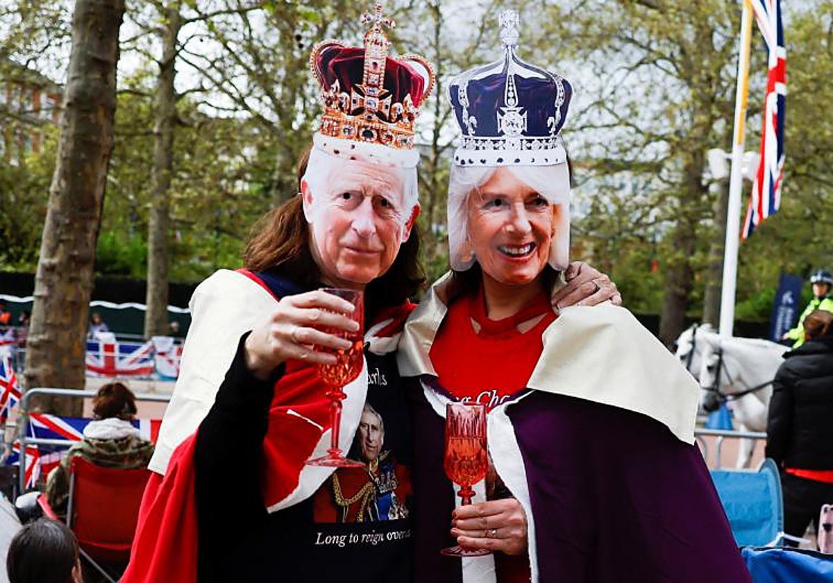 Dos ciudadanos con caretas de Carlos y Camila en las horas previas a la coronación