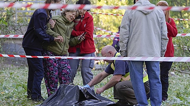 Un investigador de la policía inspecciona el cuerpo de una persona cerca de un centro de salud dañado por un ataque con misiles en Kiev