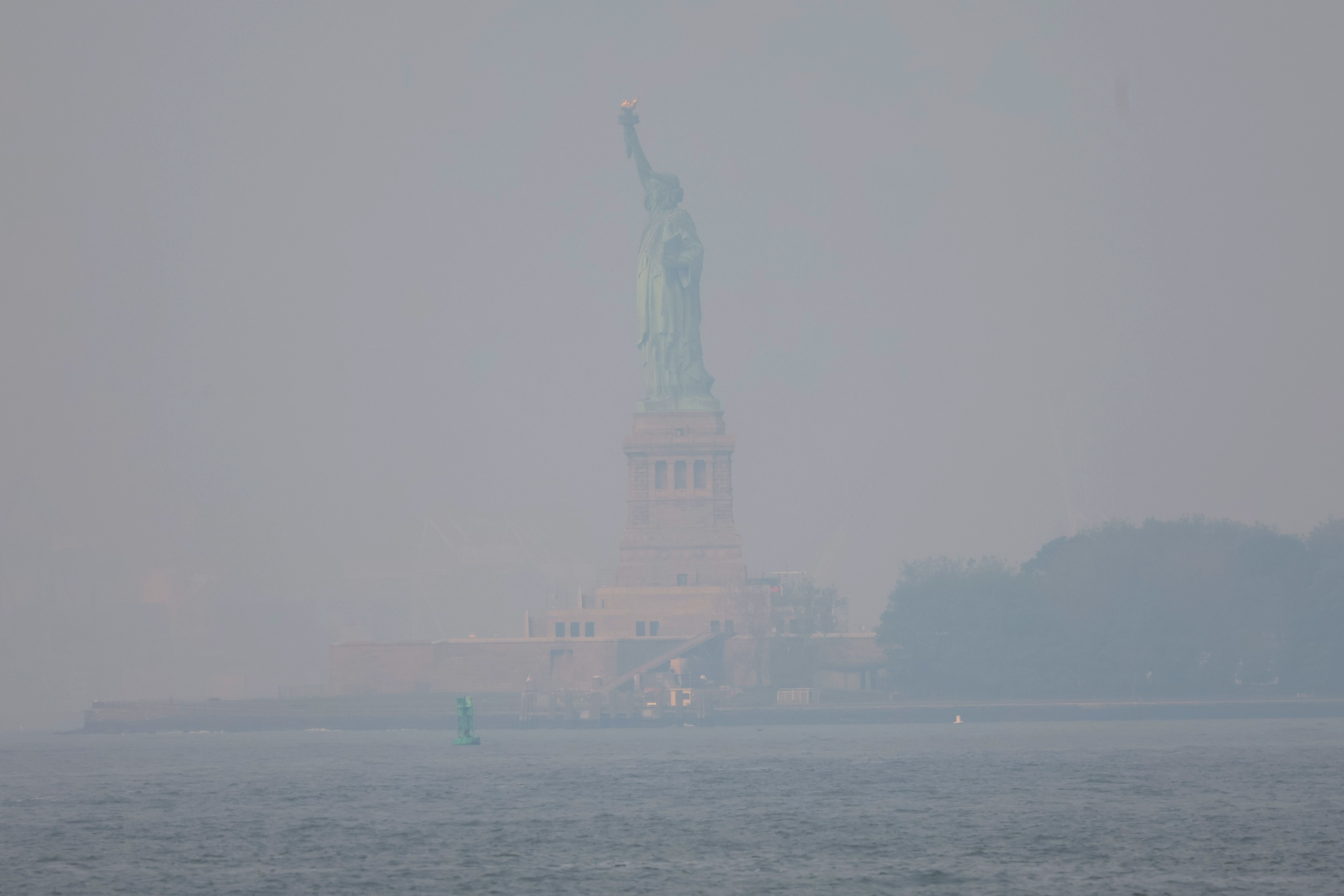 La estatua de la libertad, ayer naranja, hoy se encuentra cubierta por una densa neblina