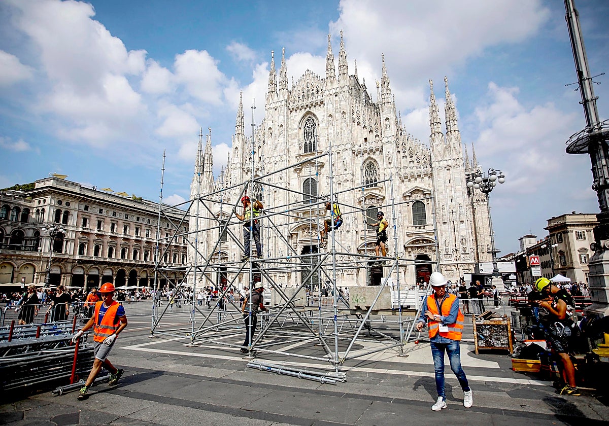 Varios trabajadores montan una estructura antes del funeral de Estado del ex primer ministro italiano Silvio Berlusconi en la plaza del Duomo de Milán