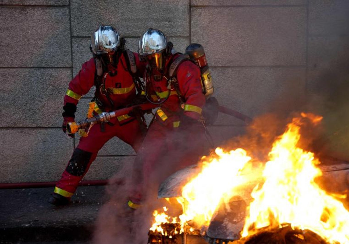 Bomberos extinguiendo el fuego de autos quemados en Nanterre, al oeste de París