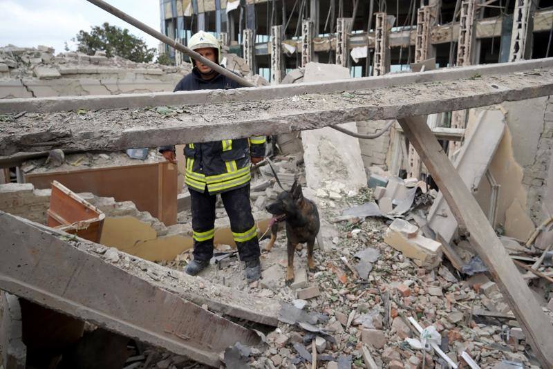 Un trabajador de los servicios de emergencia junto a su perro trabaja en los escombros del ataque en Leópolis.