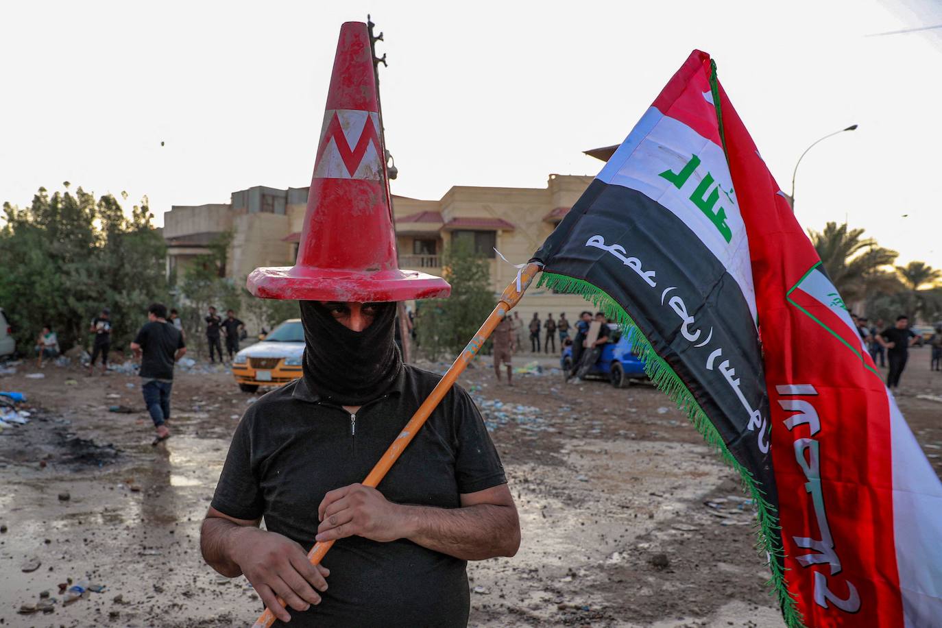 Un partidario del clérigo chií iraquí Moqtada al-Sadr con un cono de tráfico en la cabeza enmascarado y una bandera iraquí  con lemas de apoyo al profeta Mahoma  