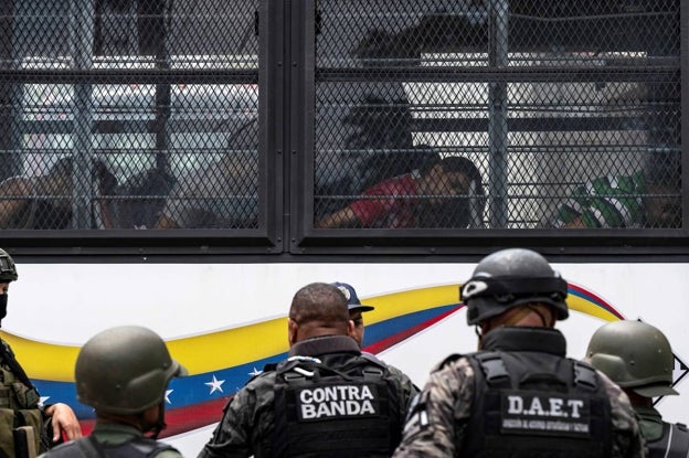 Miembros de la Guardia Nacional Bolivariana (GNB) hacen guardia mientras los reclusos a bordo de un autobús son trasladados fuera de la prisión de Tocorón