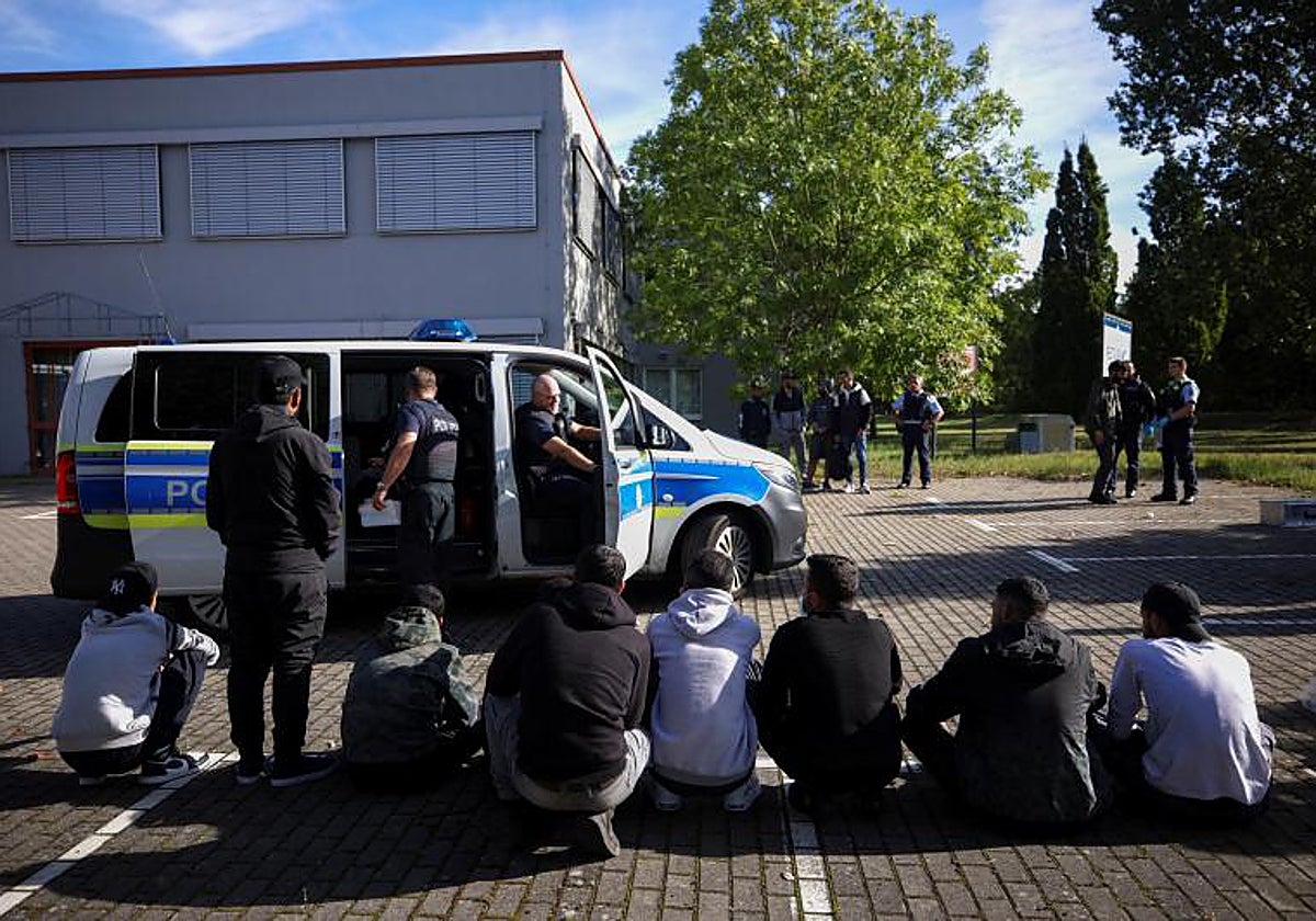 Presuntos inmigrantes ilegales se sientan en el suelo después de ser detenidos por la policía alemana durante su patrulla a lo largo de la frontera germano-polaca para impedir la migración ilegal, en Forst