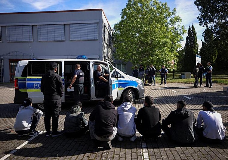 Presuntos inmigrantes ilegales se sientan en el suelo después de ser detenidos por la policía alemana durante su patrulla a lo largo de la frontera entre Alemania y Polonia para evitar la migración ilegal