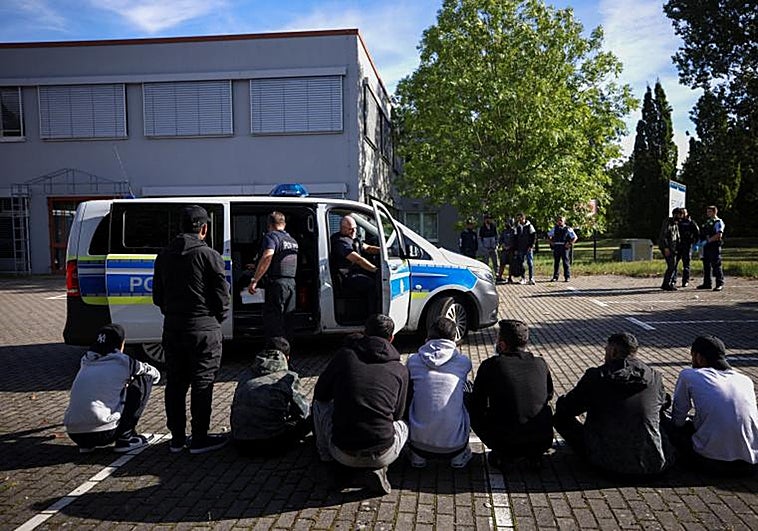 Presuntos inmigrantes ilegales se sientan en el suelo después de ser detenidos por la policía alemana durante su patrulla a lo largo de la frontera entre Alemania y Polonia para evitar la migración ilegal
