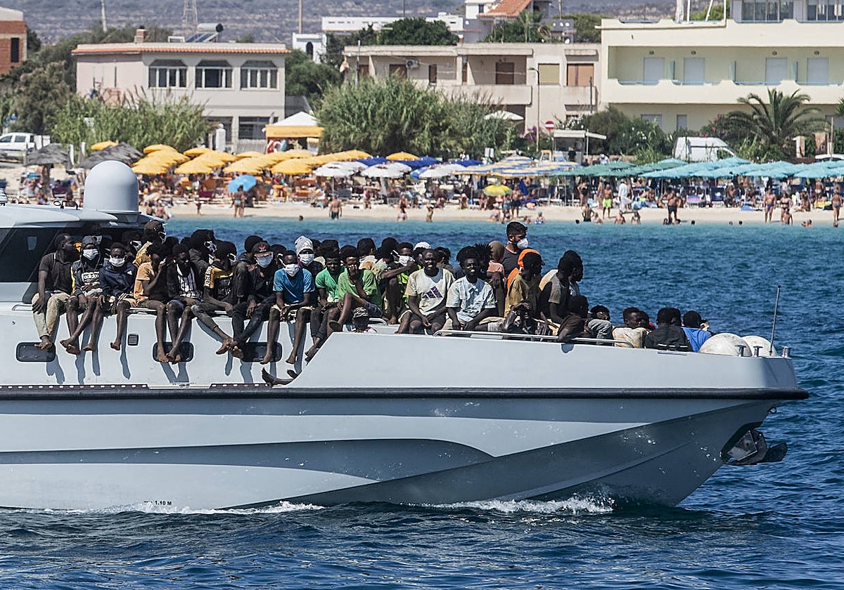 Varios inmigrantes llegan en un barco de la Guardia di Finanza al puerto de la isla italiana de Lampedusa