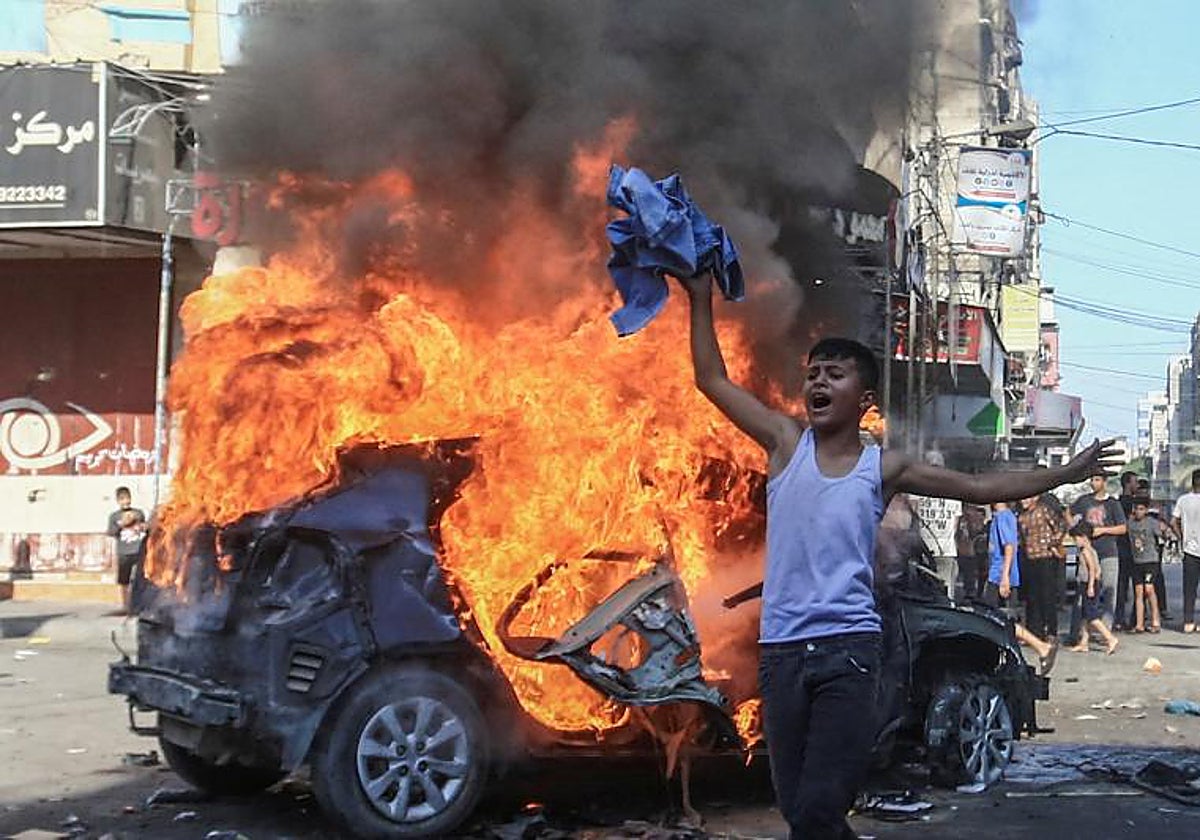 Un niño palestino junto a un vehículo israelí en llamas Gaza