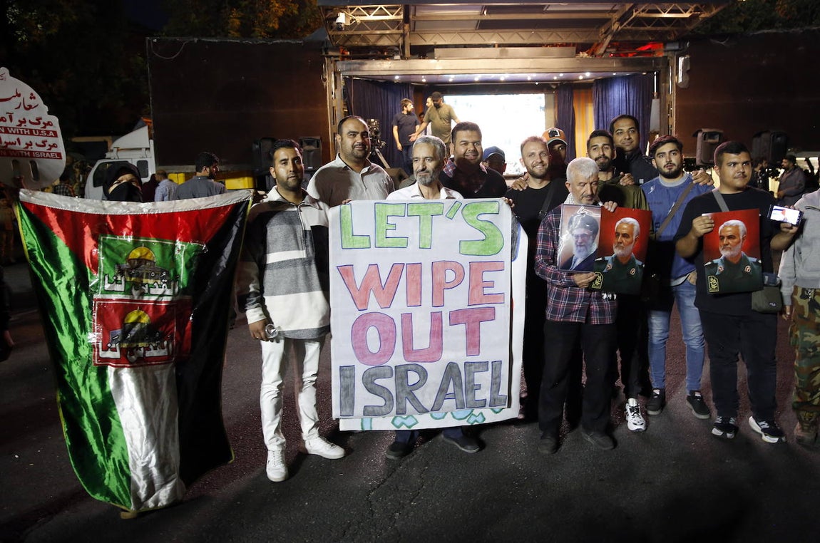 Un grupo de iraníes participan en Teherán en las celebraciones de los atentados de Hamás, sosteniendo una pancarta en la que se puede leer: «Acabemos con Israel»
