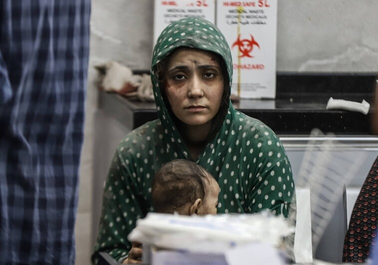 Una mujer herida en un bombardeo israelí espera asistencia médica con su bebé en el hospital Shifa de Gaza