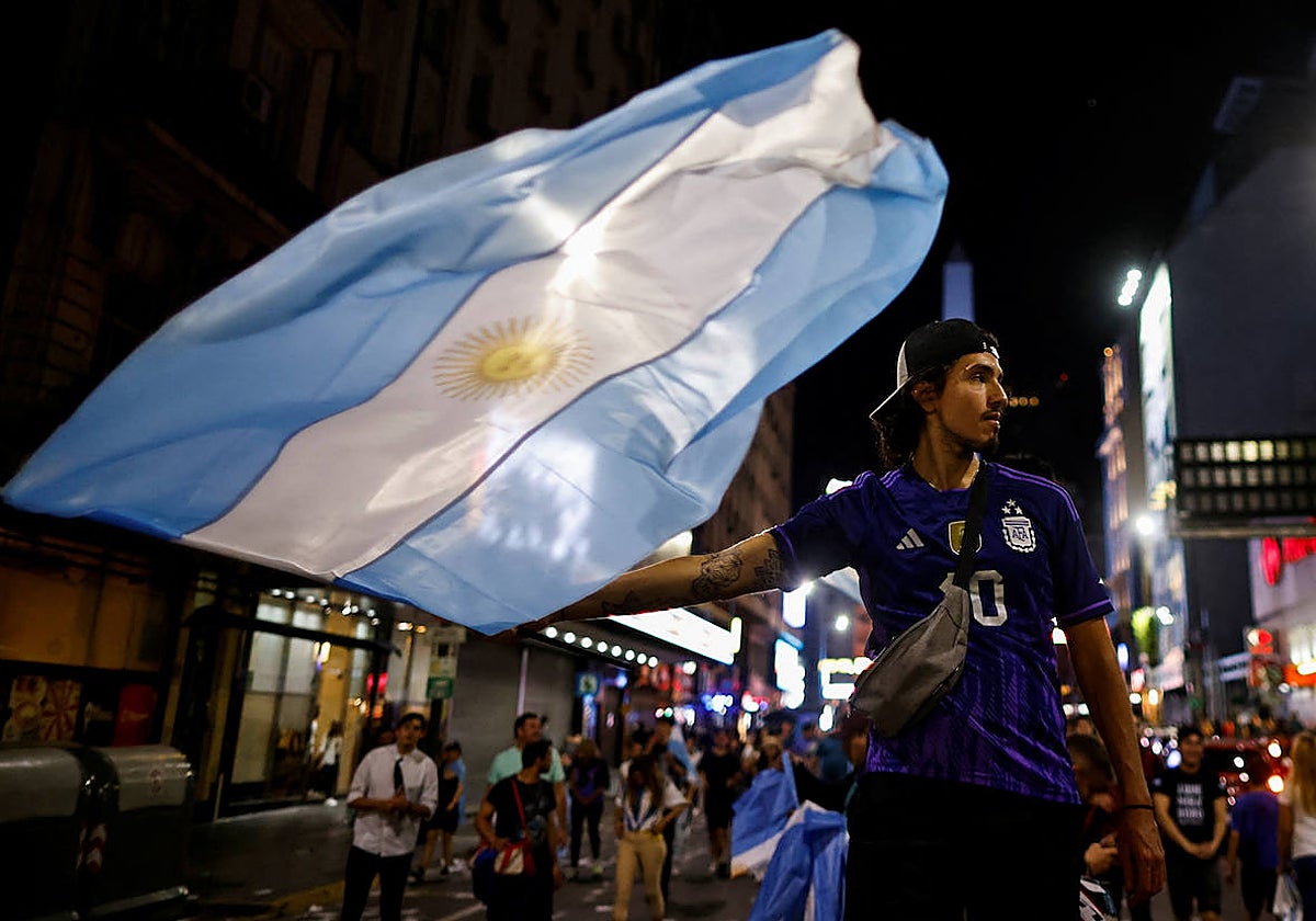 Un joven celebra con una bandera argentina la victoria de Milei