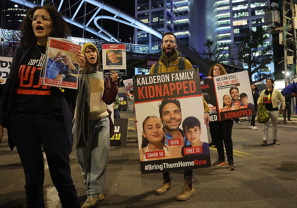 Un hombre sostiene paneles con las fotografías de rehenes en una protesta en Tel Aviv