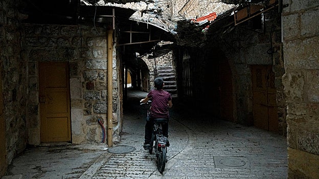 Un chico monta en bicicleta en una calle de Hebrón