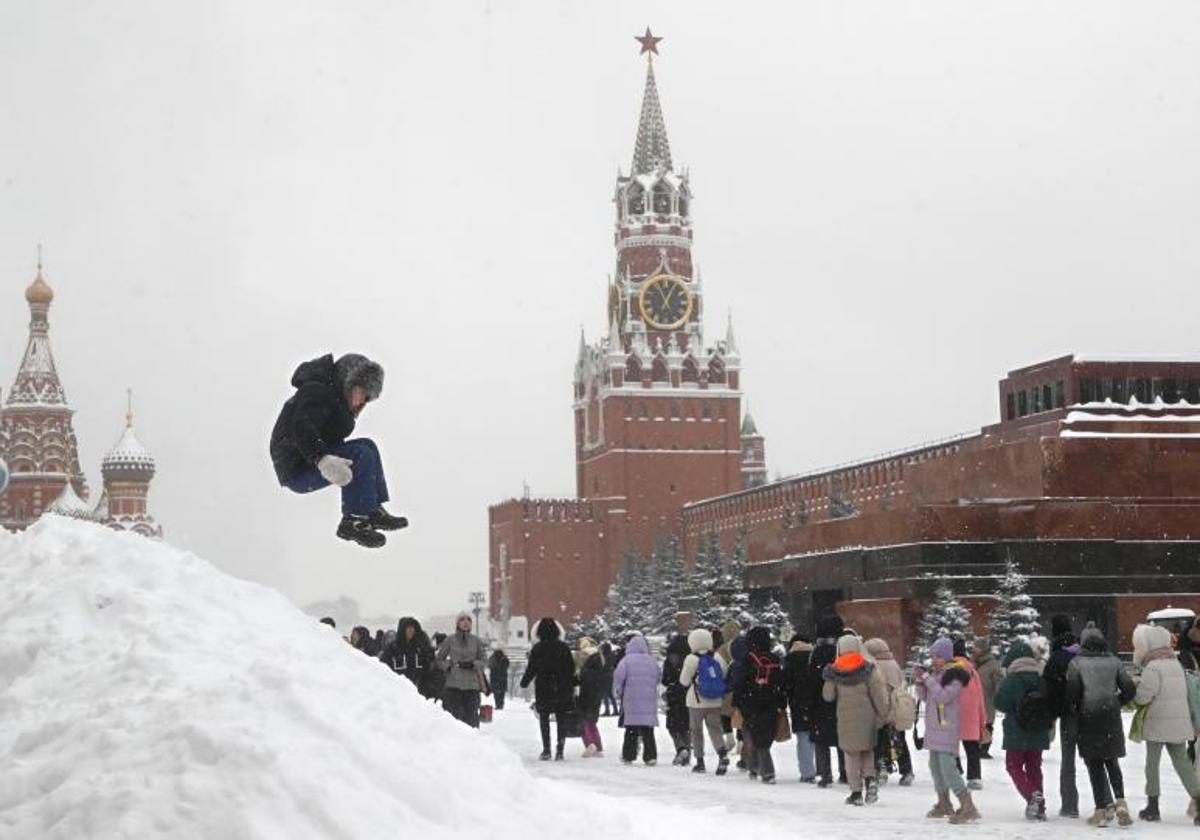 Un niño salta junto a la gente que camina por la Plaza Roja cubierta de nieve durante una fuerte nevada en Moscú