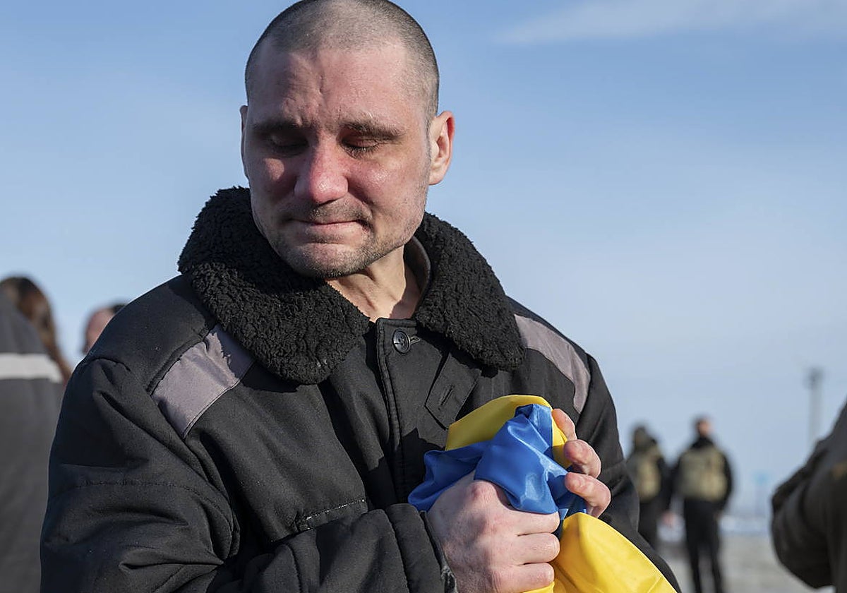 Un prisionero ucraniano estrecha entre sus manos la bandera de su país después de ser liberado