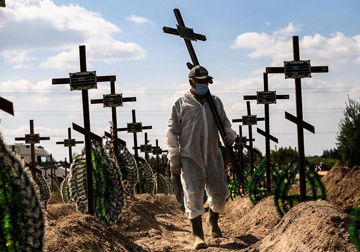 Un voluntario coloca una cruz con un número en la tumba de una de las víctimas no identificadas