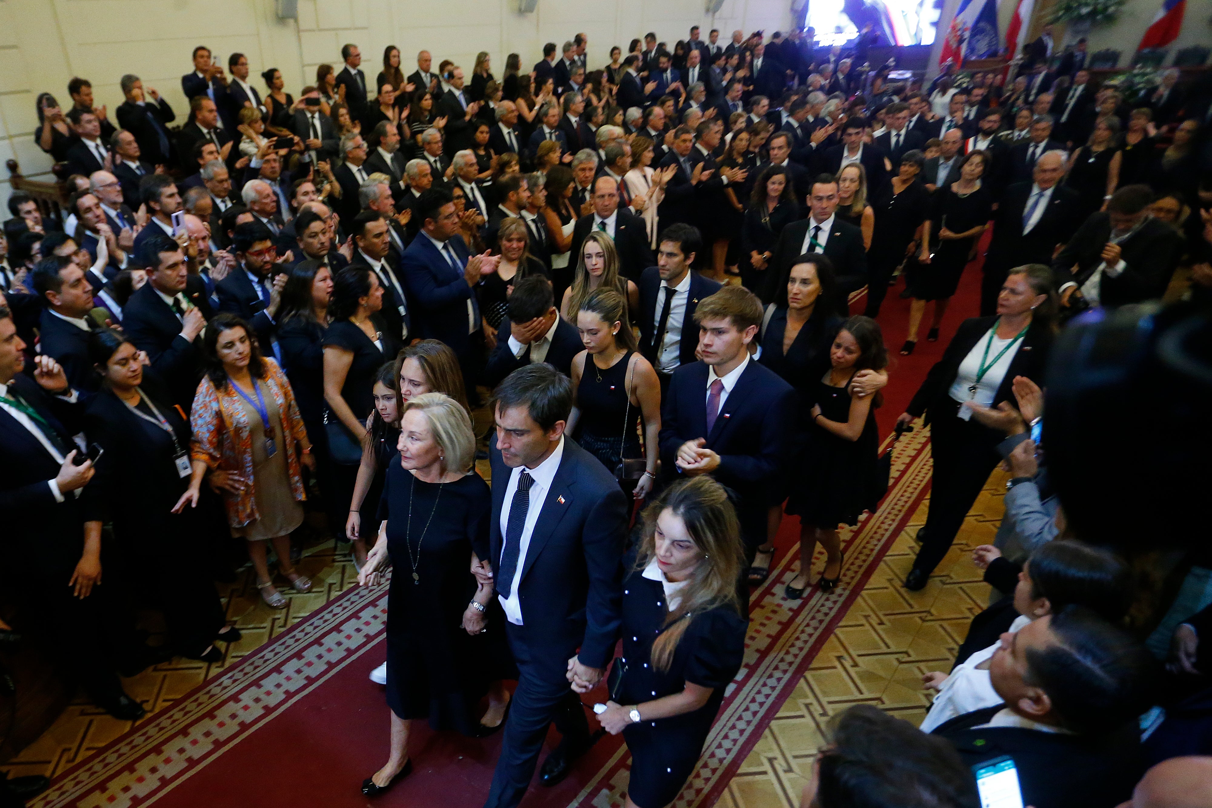 Los familiares observan el féretro que contiene el cuerpo del expresidente de Chile Sebastián Piñera salir del edificio del antiguo Congreso Nacional para su funeral en Santiago.