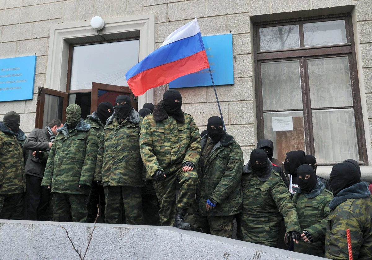 Individuos enmascarados no identificados sostienen una bandera rusa mientras bloquean el edificio del Sindicato en Semferopol , el centro administrativo de Crimea, el 1 de marzo de 2014