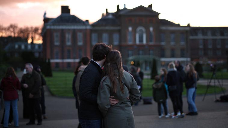 Una pareja se abraza frente al palacio de Kensington tras el anuncio de que la Princesa tiene cáncer