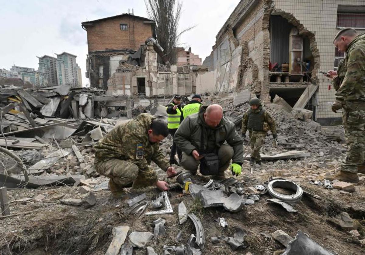 Agentes policiales ucranianos examinan fragmentos de un misil en el lugar del ataque con misiles en Kiev