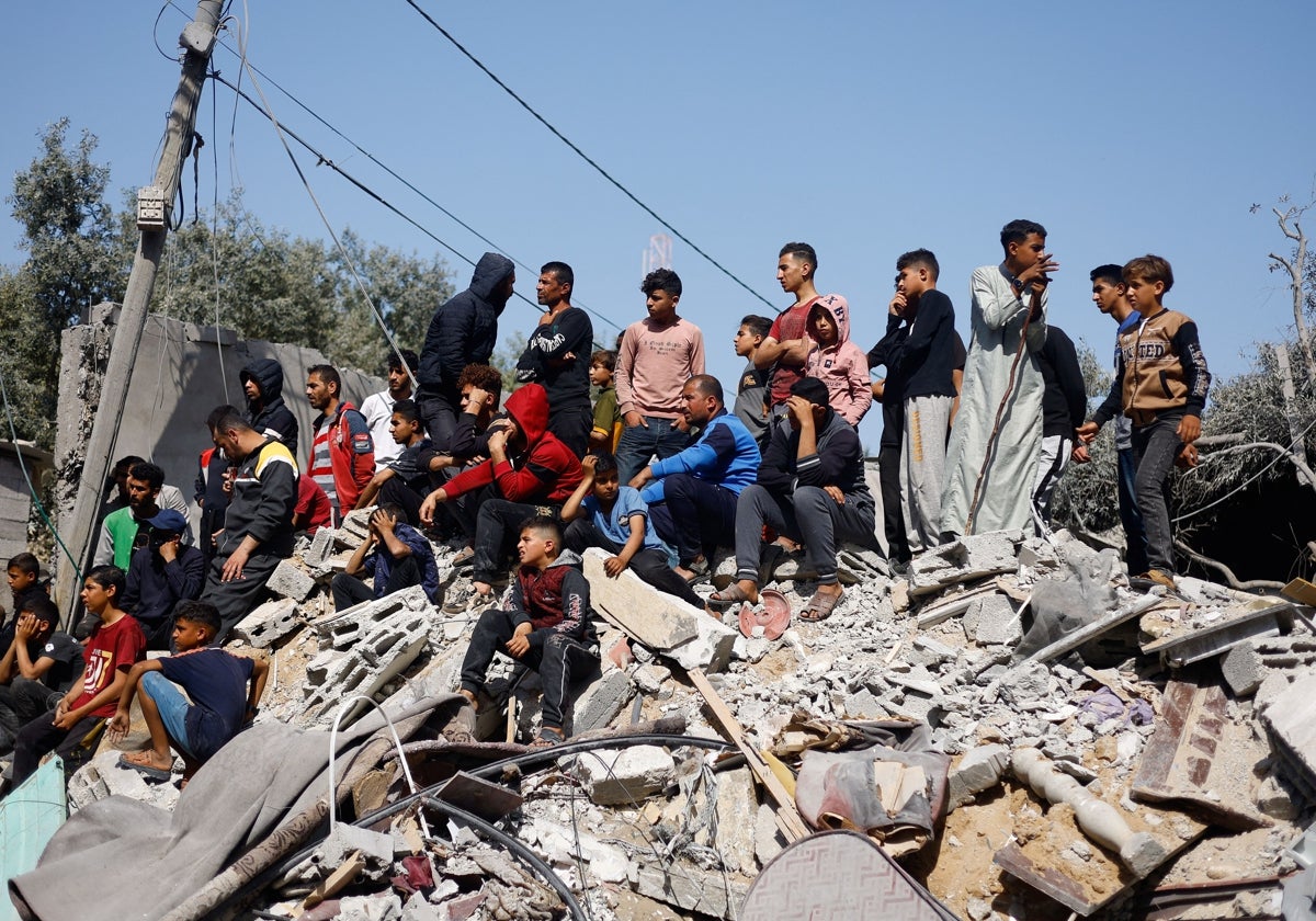 Palestinos se reúnen sobre los escombros de un edificio derribado en un ataque israelí