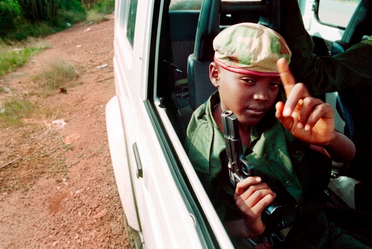 En esta fotografía del 9 de junio de 1994, un niño armado está sentado en un automóvil con partisanos del Frente Patriótico Ruandés (FPR) patrullando las calles de Kigali, Ruanda