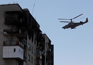 Un helicóptero de ataque ruso Ka-52 'Alligator' vuela cerca de un edificio residencial dañado durante el conflicto en Ucrania