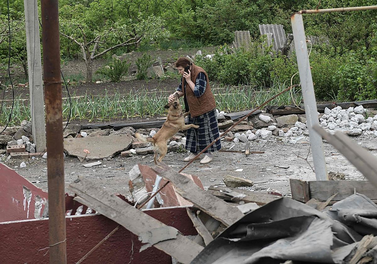 Una mujer acaricia a un perro junto a un apartamento dañado por los recientes bombardeos.