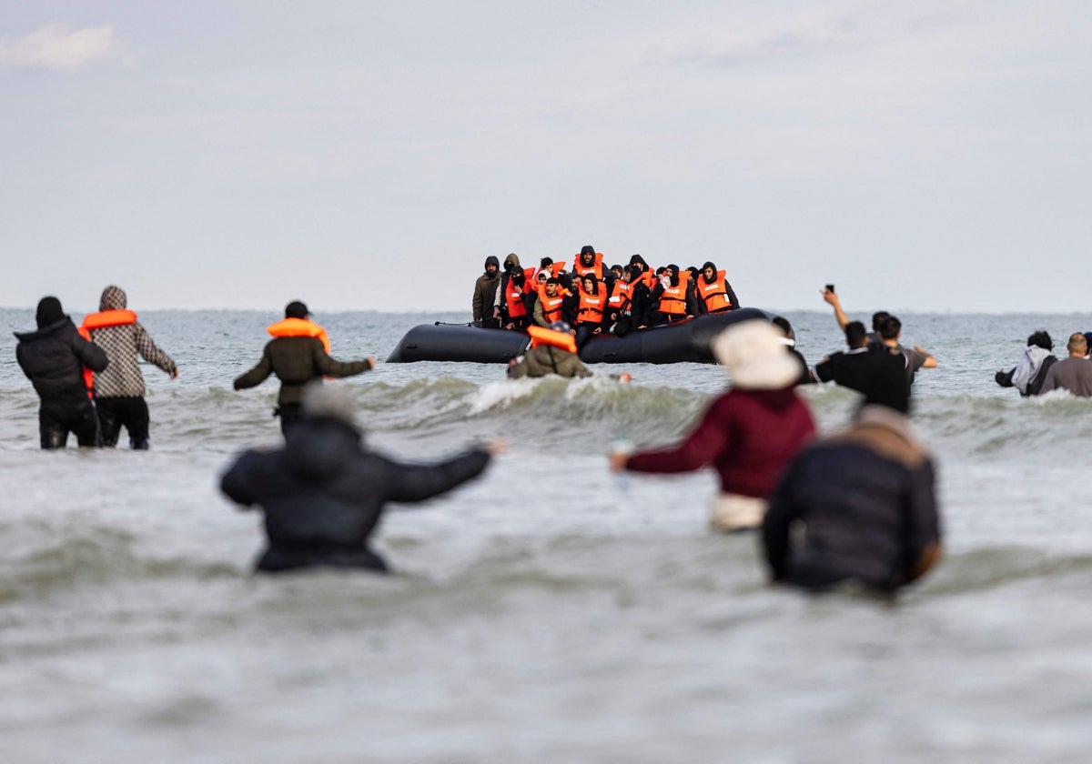 Unos migrantes saludan al barco de un contrabandista en un intento de cruzar el Canal de la Mancha, al norte de Francia