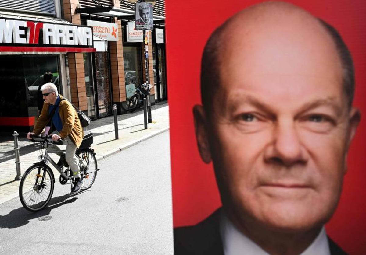 Un hombre pasa en bicicleta junto a un cartel electoral del partido socialdemócrata SPD de Alemania que representa al canciller alemán Olaf Scholz en Frankfurt am Main