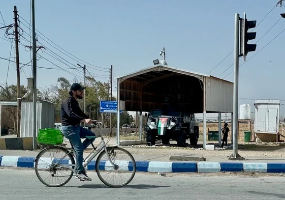 Un refugiado sirio sale a trabajar del campo de Zaatari, cuya entrada está vigilada por una tanqueta blindada del Ejército jordano
