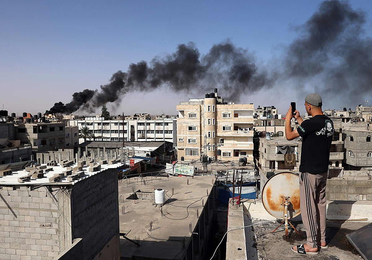 Un hombre toma una fotografía con su teléfono de los bombardeos en Rafah