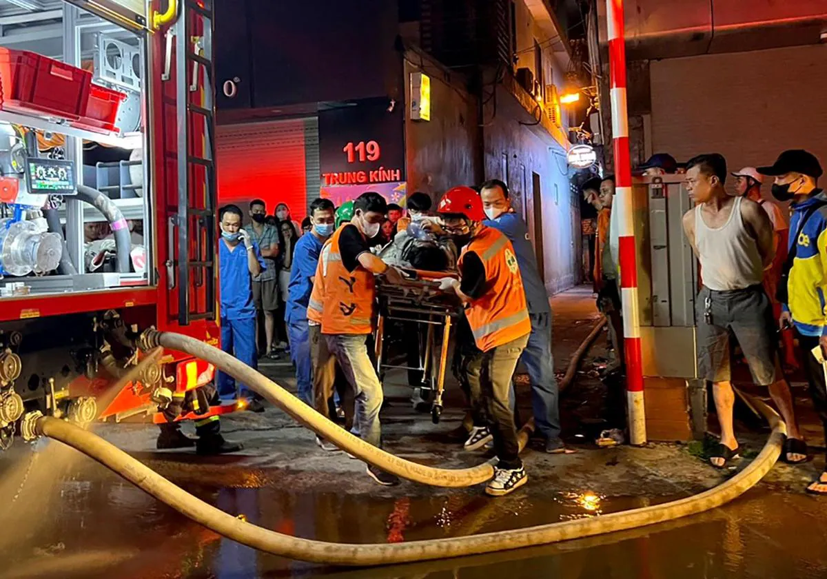 Los servicios de emergencia trasladando una víctima a una ambulancia tras el gran incendio en un bloque de apartamentos en Hanoi