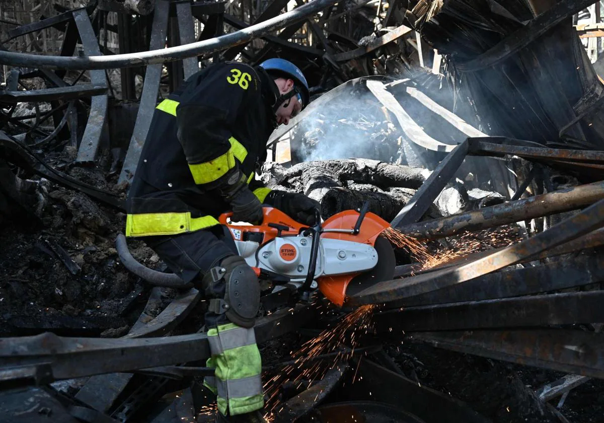 Un empleado del Servicio Estatal de Emergencia de Ucrania corta los escombros de un supermercado