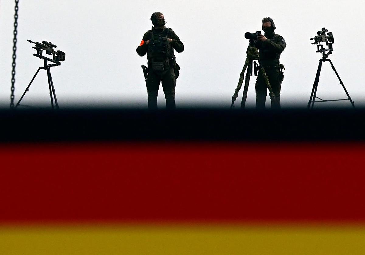 Miembros de la policía se encuentran cerca de sus armas en el techo de la casa Paul Loebe