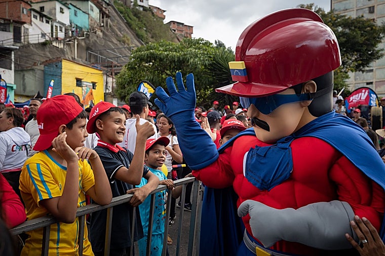 Un hombre con el disfraz de Super Bigote saluda a niños durante una marcha chavista en apoyo a Maduro
